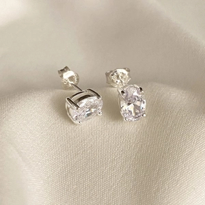 Elegant 925 sterling silver oval-cut zircon stud earrings on textured beige fabric