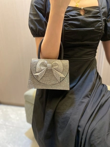 Detail of silver rhinestone evening bag featuring a large sparkling crystal bow