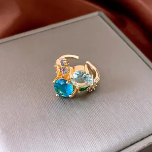 Golden hollow geometric open ring with colorful zircon stones on luxury display stand