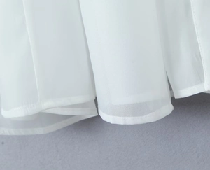 Detailed close-up of double-layered white chiffon dress hem with fine stitching