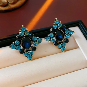 Dettaglio macro di orecchini vintage in oro con cristalli blu su cuscinetto