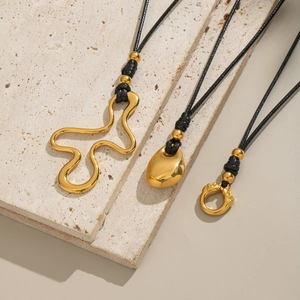 Trois colliers avec pendentifs dorés irréguliers et cordons noirs sur base en pierre