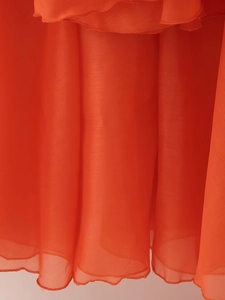 Detail view of lightweight red chiffon fabric featuring delicate textures and hemmed edges