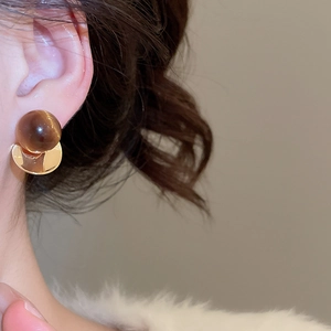 Close-up of 18k gold plated bird stud earring featuring a brown tiger eye stone bead