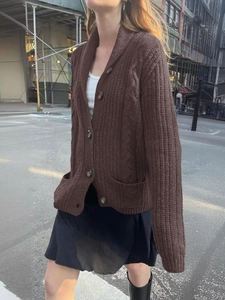 Detail view of brown cable-knit cardigan featuring buttons and functional front pockets