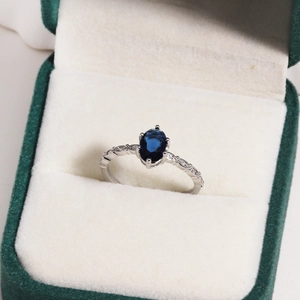 Macro view of oval blue zircon ring with silver band in a velvet jewelry box