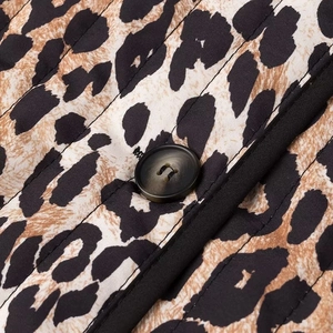 Macro shot of quilted leopard print fabric detail with button and black piping trim