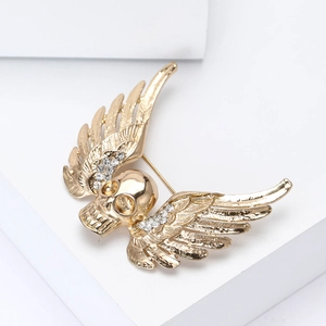 Detail of gold winged skull brooch with white rhinestones on geometric blocks
