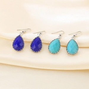 Détail de boucles d'oreilles goutte en verre avec bordure argentée sur soie