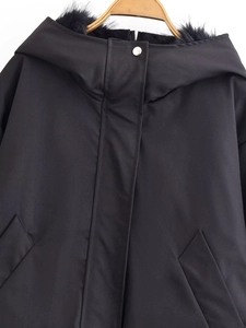 Detail view of women's black hooded parka featuring faux fur trim and silver snaps