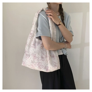 Detail of floral butterfly embroidery on white lace tote bag worn on shoulder