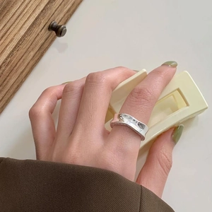 Detailed view of irregular wavy silver ring with mirror finish on model index finger