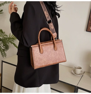 Detail of vintage brown leather tote bag featuring a decorative wide woven shoulder strap