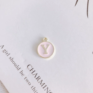 Detail of round golden letter Y pendant with pink enamel for DIY jewelry crafting