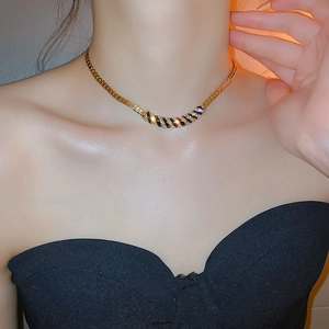 Close-up of a gold necklace with black striped pendant and rhinestones on a model