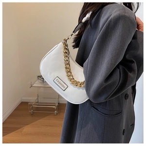 Detail of white half-moon underarm bag with thick gold chain and fashion label on blazer