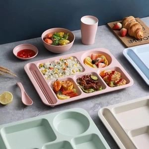 Pink wheat straw divided dinner plate set with bowl and cup on a gray textured surface