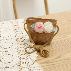 Close-up of a woven straw mini crossbody bag with fabric pink rose flower detail