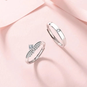S925 sterling silver angel wing couple rings set with cubic zirconia on pink background