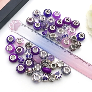 Makro-Detail violetter DIY-Perlen aus Legierung und Glas mit Lineal für Größe