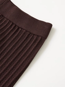 Dettaglio dei pantaloni in maglia marrone scuro con elastico a coste e trama a rete