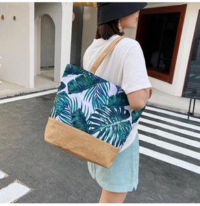 Detailed street style shot of palm leaf print canvas tote bag worn by a model