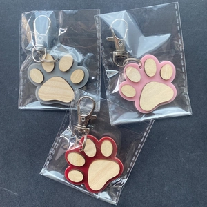 Three creative wooden paw print keychains in gray, pink, and red with metal lobster clasps