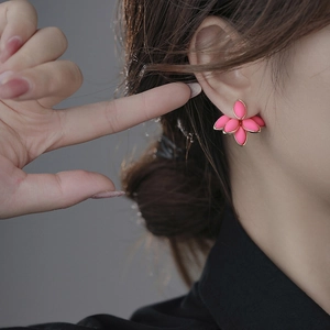 Detailed view of rose pink petal earrings with gold edges worn by a female model