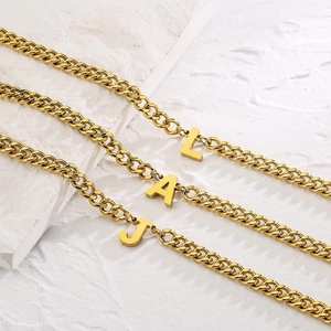 Macro shot of 18K gold Cuban link necklaces with uppercase letter pendants L A and J
