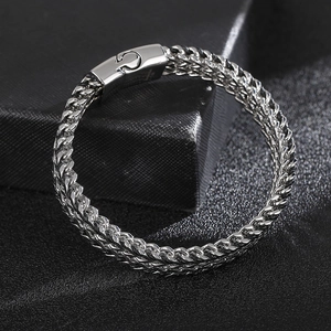 Macro detail of silver keel chain bracelet with polished magnetic clasp on black leather