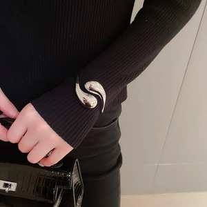 Detailed view of silver water drop open cuff bracelet styled over a black knit sleeve