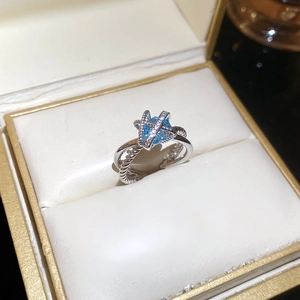 Detail of cross-over ring featuring blue star gemstone and sparkling micro-pave crystals
