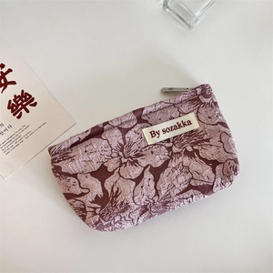 Close-up of embossed floral textured pouch in vintage pink with silver zipper and tag