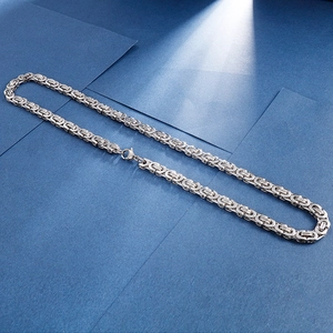 Macro shot of silver Byzantine link chain with square clasp on blue background
