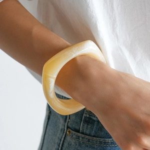 Detailed shot of marbled resin chunky bangle with cream and white swirls on model
