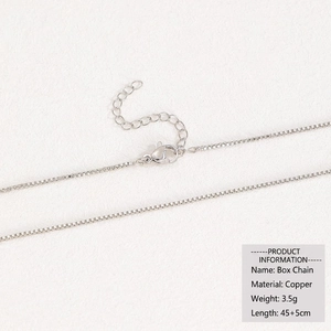 Macro detail of 18k silver box chain necklace with lobster clasp and copper material