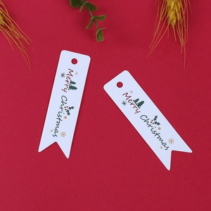 Dettaglio di etichette regalo bianche Merry Christmas con motivi di alberi su rosso