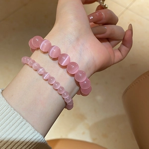 Detailed view of pink cat eye stone bead bracelets in different sizes on wrist