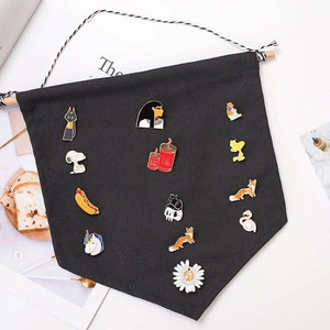 Detail of black triangular canvas banner displaying enamel pins with a wooden hanging rod