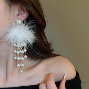 Detail of elegant white feather earrings with layered pearl tassels worn by a model