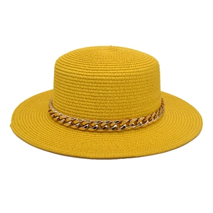Détail d'un chapeau de paille jaune vif avec une grosse chaîne dorée décorative