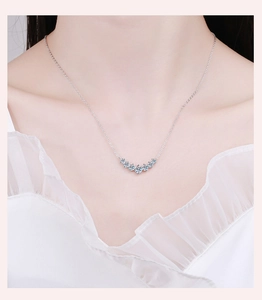 Close-up of minimalist silver necklace with seven blue moissanite stones on a female neck