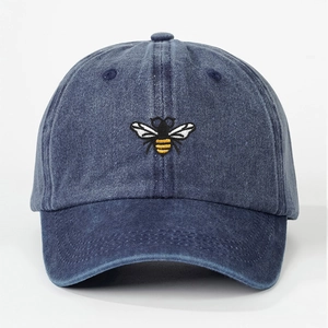 Washed denim baseball cap in navy blue featuring a detailed bee embroidery on the front