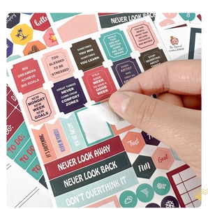Close-up of hand peeling colorful motivational English planner stickers from a sheet