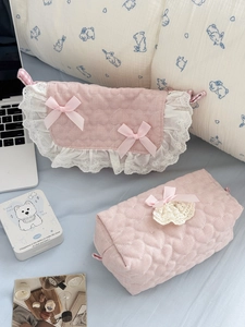 Detail of pink heart-quilted makeup bags featuring delicate lace trim and ribbon bows