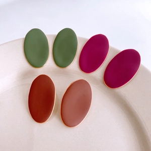 Minimalist matte oval earrings in olive, burgundy, and brown with gold trim on tray