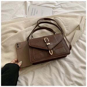 Détail du sac à bandoulière marron foncé avec coutures géométriques et boucle dorée en forme de U
