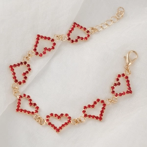 Elegant gold heart bracelet with red rhinestones and lobster clasp on white fabric background