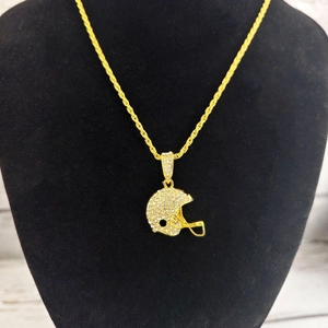 Détail d'un pendentif casque de football doré serti de strass sur une chaîne torsadée