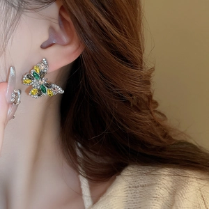 Close-up of butterfly drop earrings with colorful crystals worn by a model